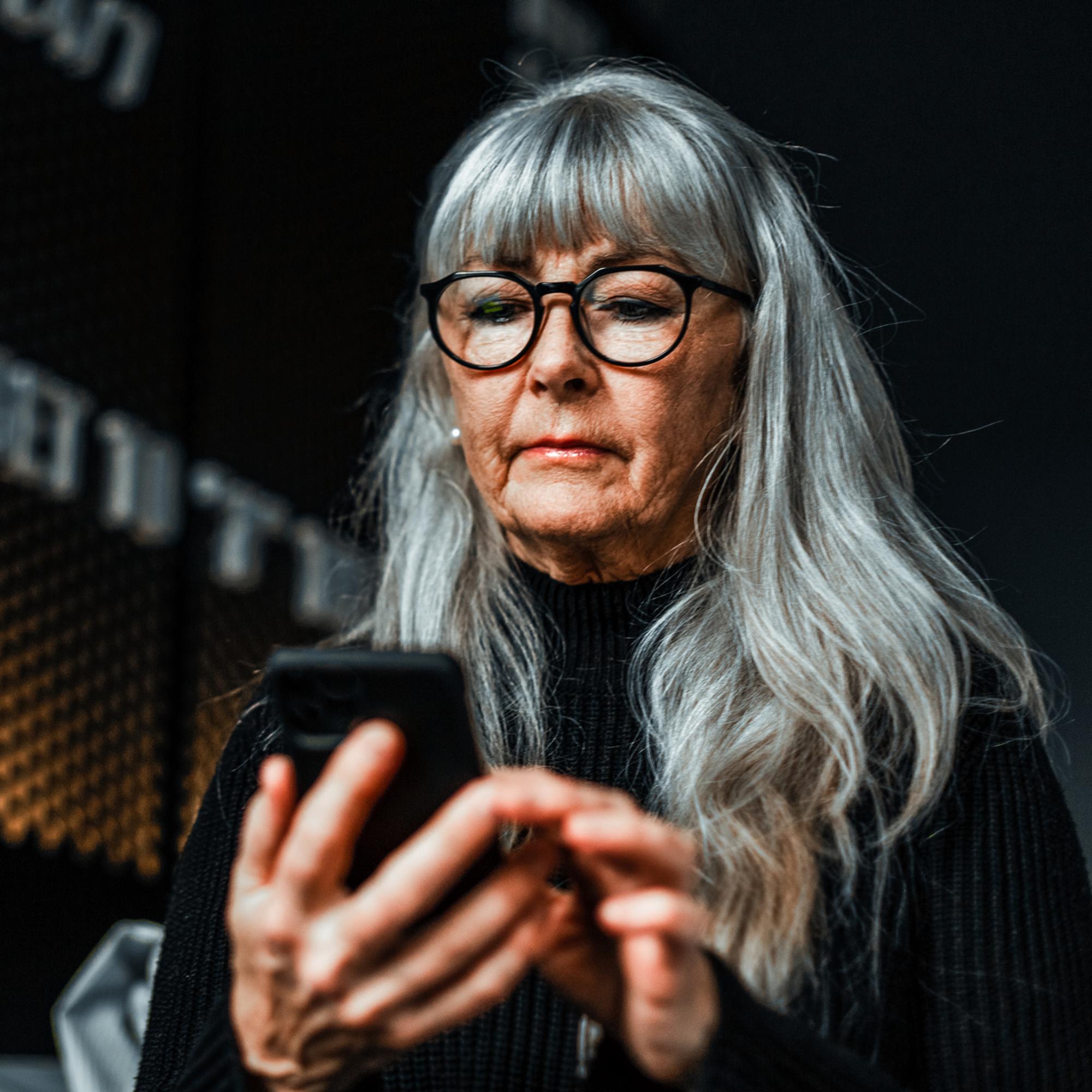 Gråhårig kvinna med mobil.