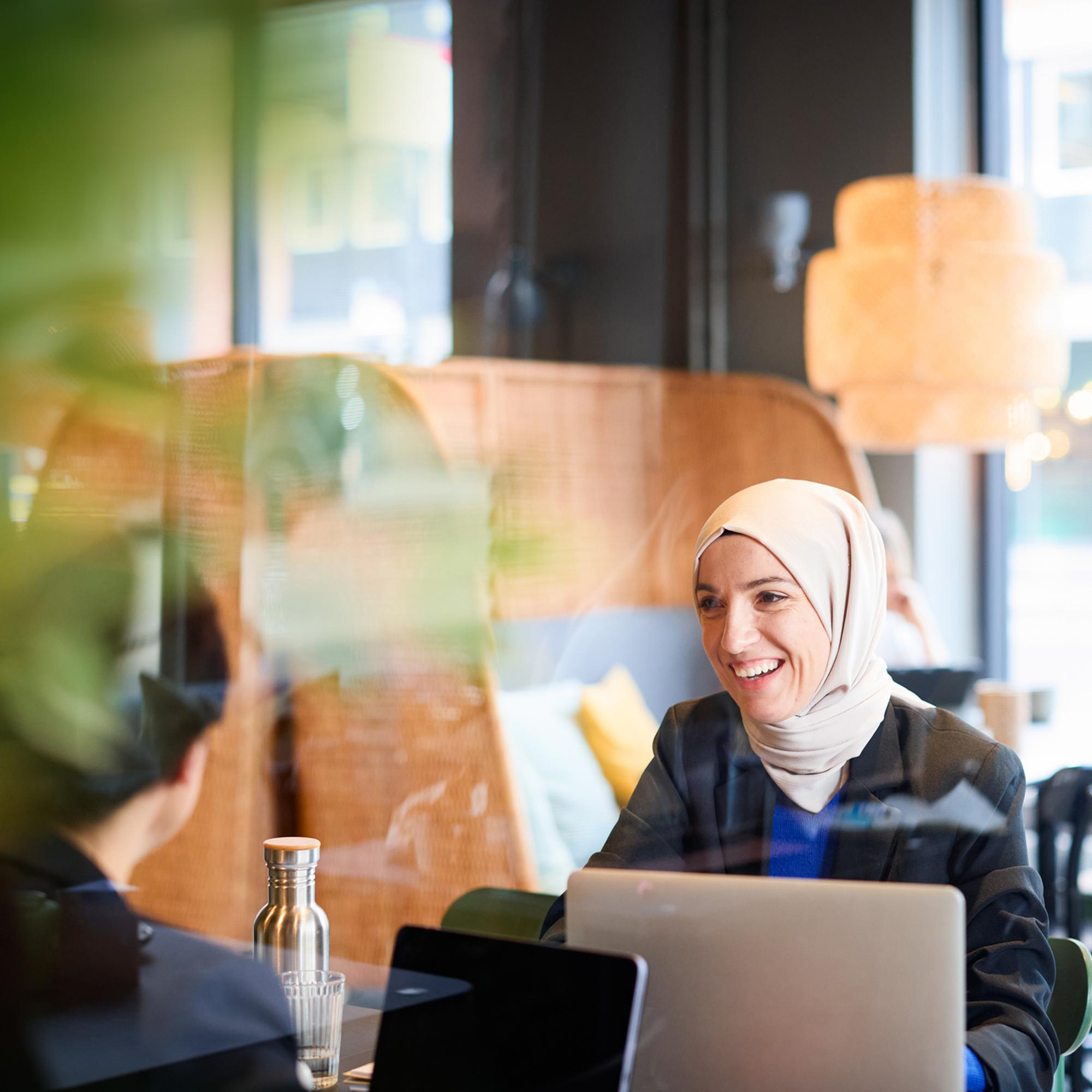 Kvinna med hijab på affärsmöte på café