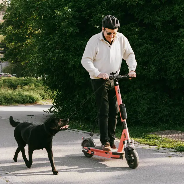 En man på en elsparkcykel med en hund.