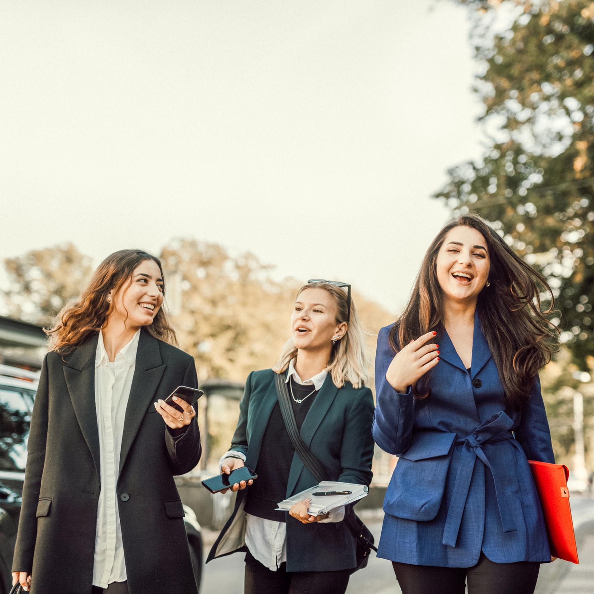 Tre glada kvinnor är ute och promenerar.