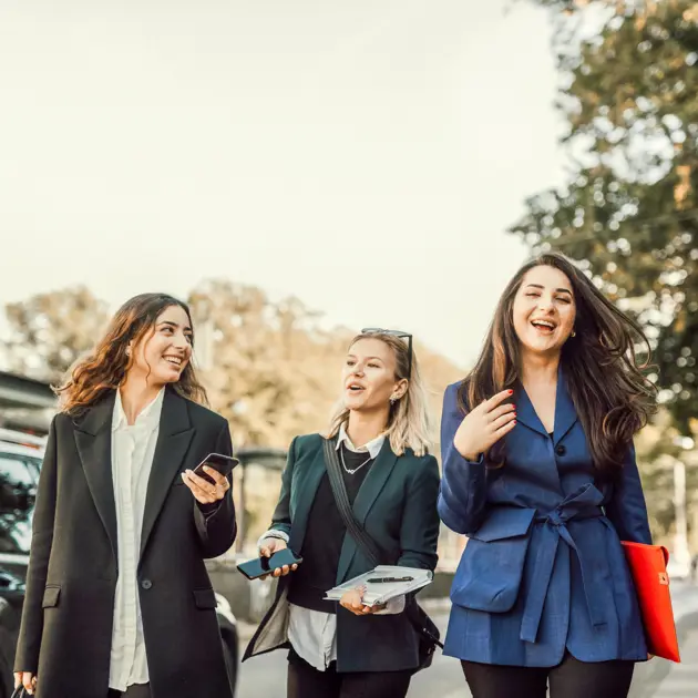 Tre glada kvinnor är ute och promenerar.