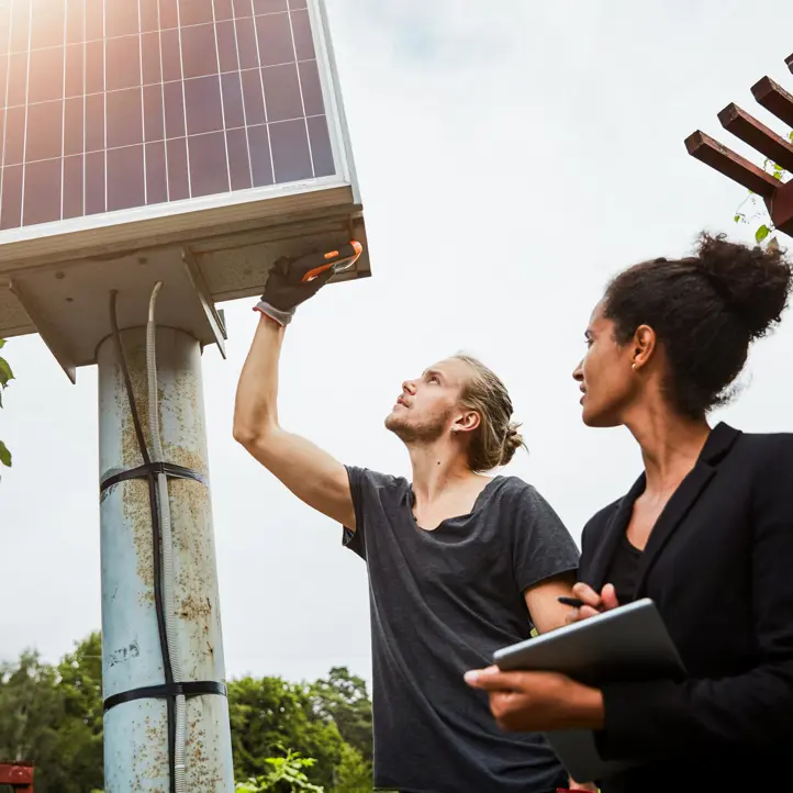 Två unga människor mäter på solpaneler.