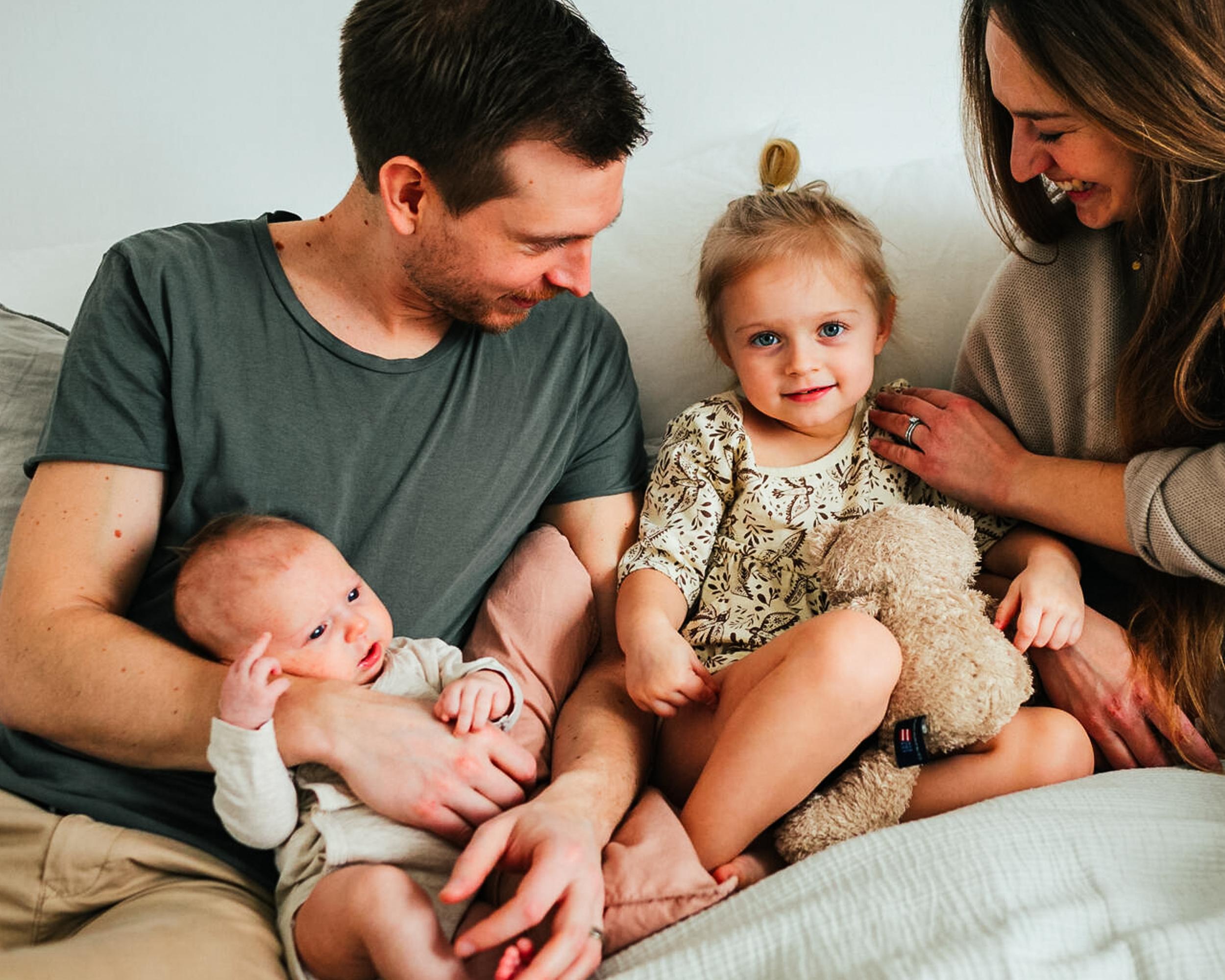 Familj sitter i säng bebis barn.