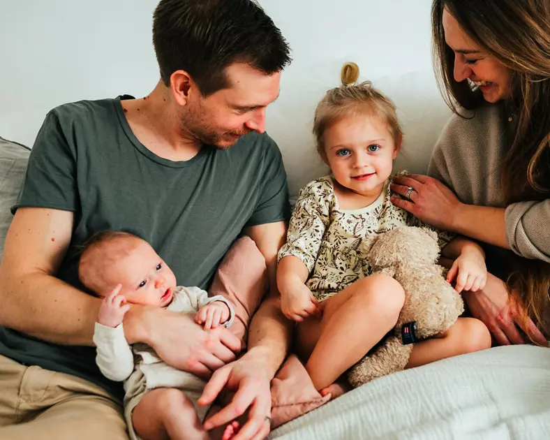 Familj sitter i säng bebis barn.