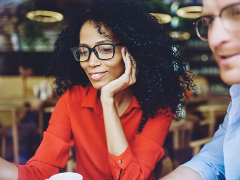 Kvinnlig kollega med glasögon samtalar med manlig kollega på ett café