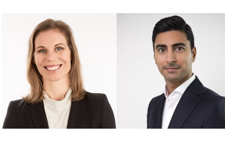 Två personer i affärsdräkter står mot en vit bakgrund, en leende kvinna med axellångt hår och en man med kort, mörkt hår