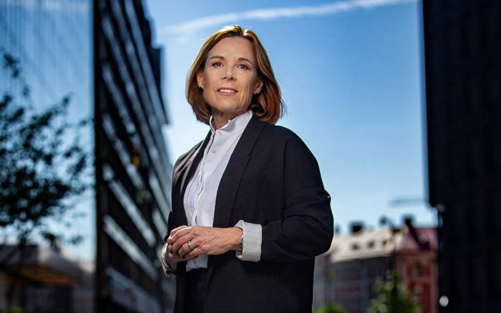 Åsa Wallenberg i formell klädsel utomhus i en stadsmiljö med blå himmel i bakgrunden