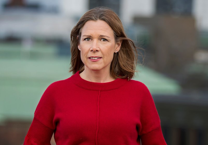 Åsa Wallenberg i röd tröja framför suddig bakgrund utomhus