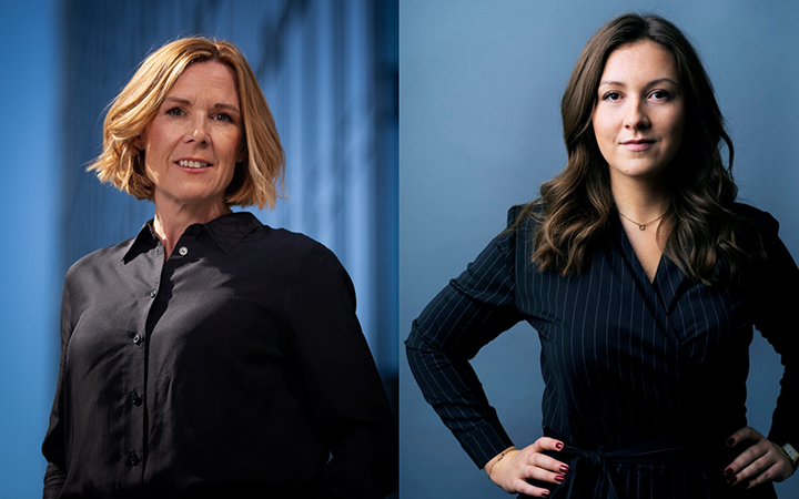 Två kvinnor i professionella kläder poserar mot en blå bakgrund