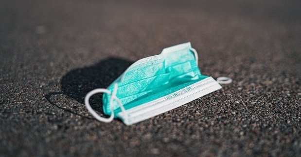 Grön ansiktsmask på asfalt, symboliserar miljöproblem och avfallshantering