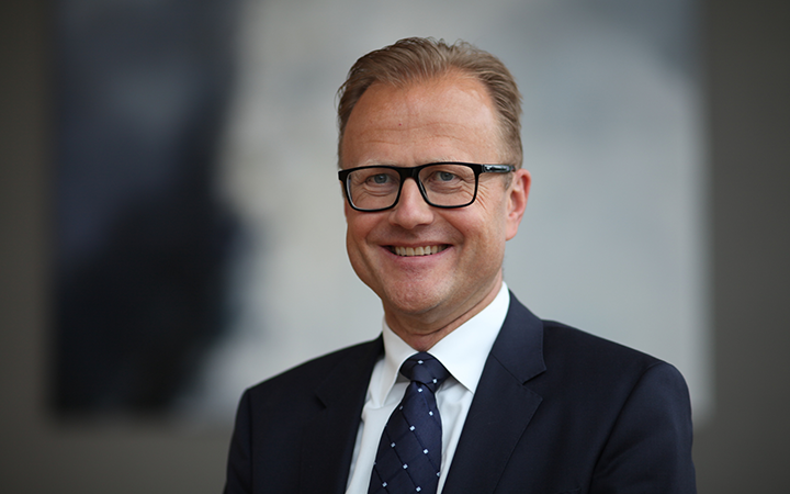 Man i kostym med glasögon och slips, leende i en professionell miljö