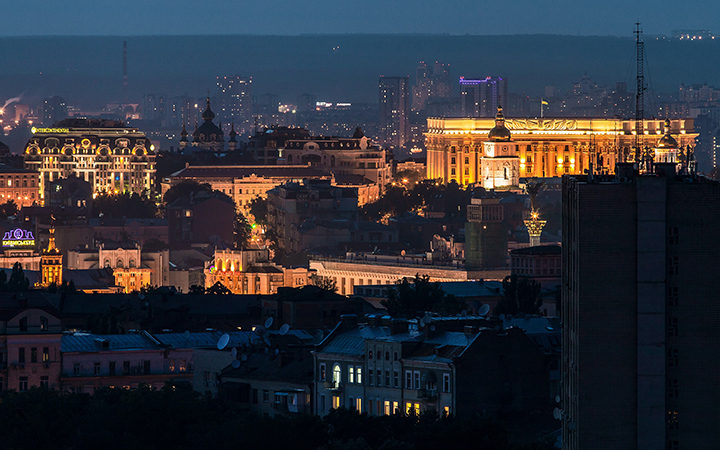 Nattvy över Kyiv med upplysta historiska byggnader och moderna skyskrapor