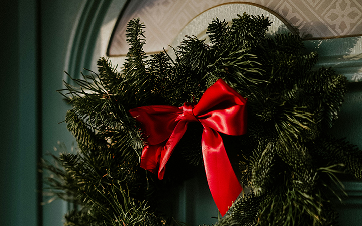 Julkrans med röd rosett hängande på en dörr