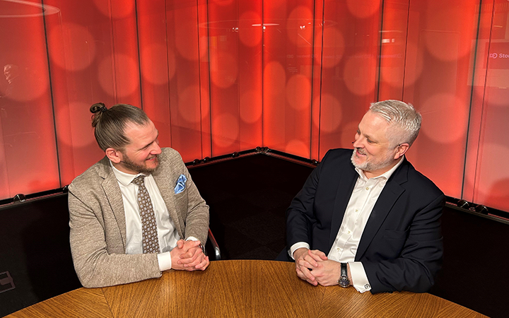 Två affärsmän diskuterar vid ett möte i ett rum med röd bakgrund