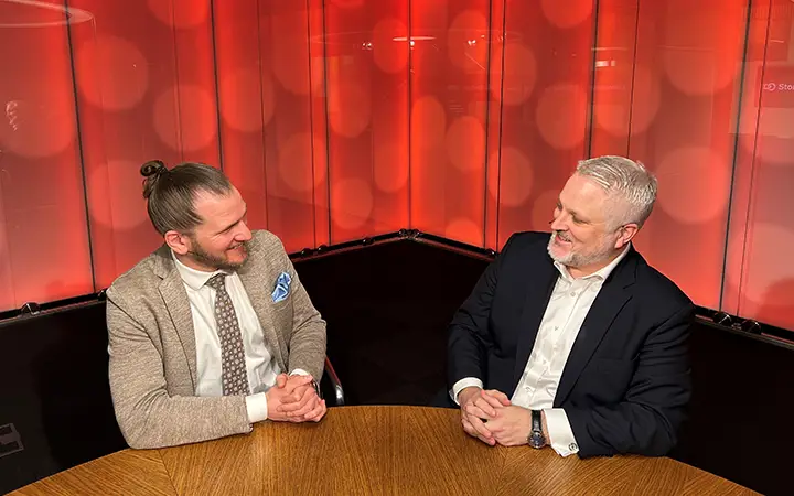 Två affärsmän diskuterar vid ett möte i ett rum med röd bakgrund