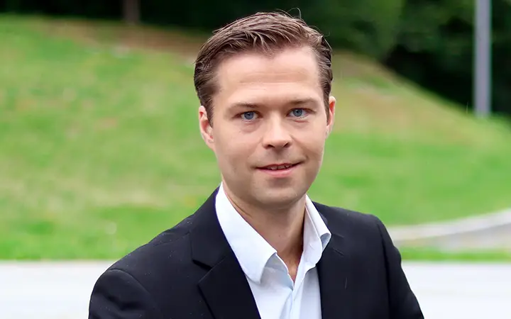 Geir Magne Boe i kostym framför en grönskande bakgrund