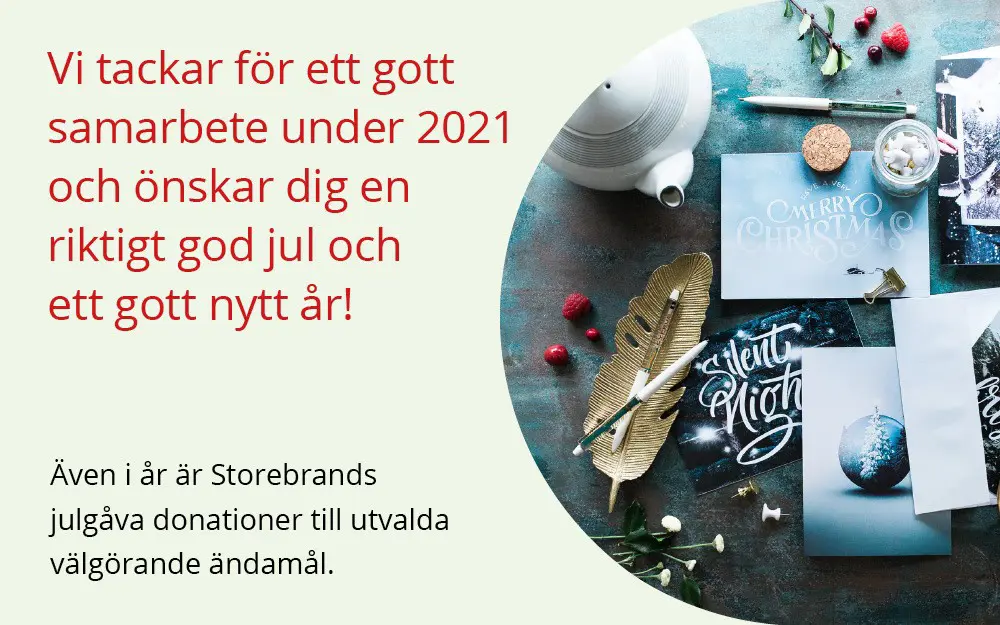 Julhälsning från Storebrand med kort och dekor på ett bord, inklusive meddelanden som önskar god jul och gott nytt år samt information om donationer till välgörenhet