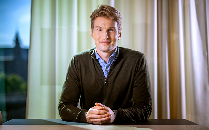 Gustaf Linnell i kostym i ett modernt kontorslandskap med glasväggar