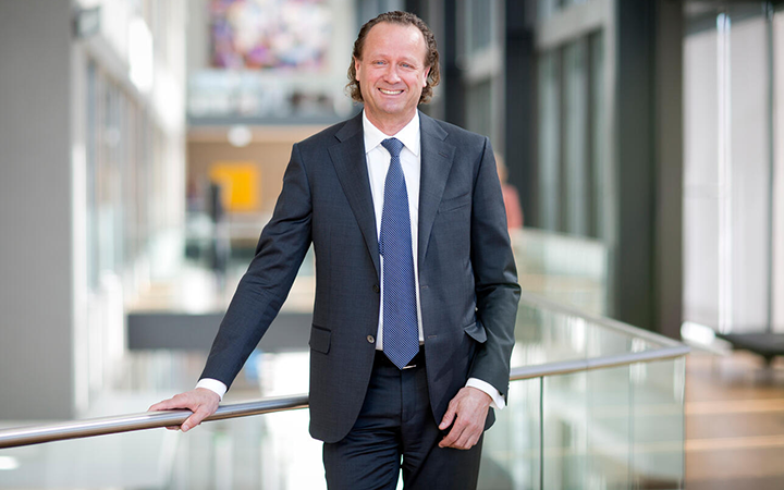 Man i kostym står leende i en modern kontorsmiljö