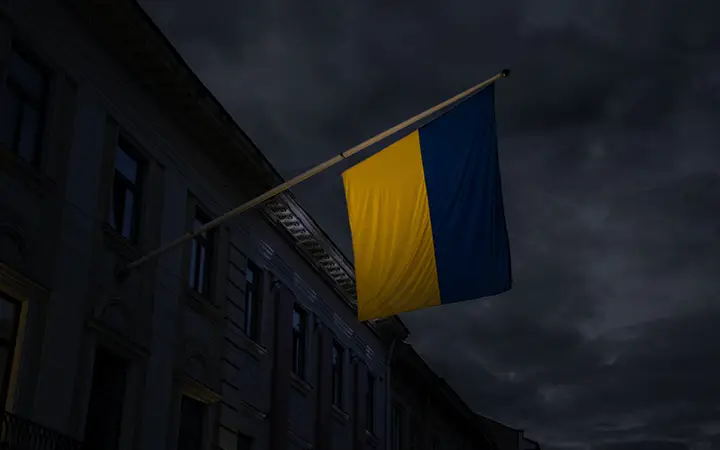 Ukrainsk flagga vajar mot en mörk natthimmel, vid sidan av en historisk byggnad