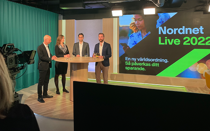 Fyra personer vid ett bord under Nordnet Live 2022, med en stor skärm i bakgrunden som visar texten "En ny världsordning. Så påverkas ditt sparande."