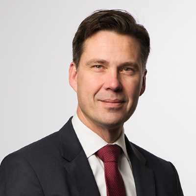 Man i kostym med röd slips, mot vit bakgrund