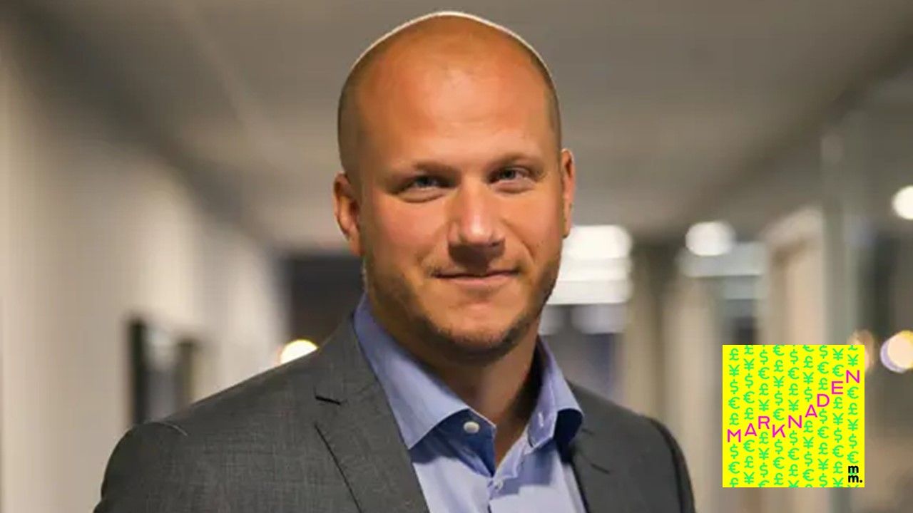 Man i kostym stående i kontorsmiljö, ser in i kameran