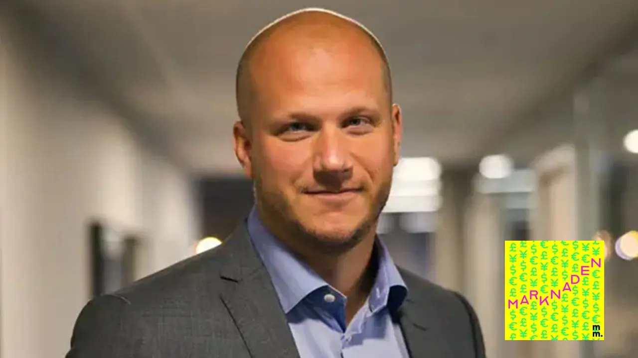 Man i kostym stående i kontorsmiljö, ser in i kameran