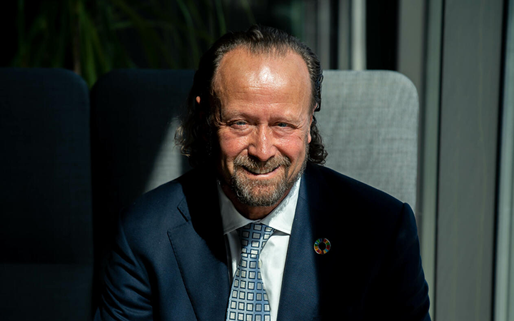 Jan Erik Saugestad i kostym med slips, sittandes i ett solbelyst rum