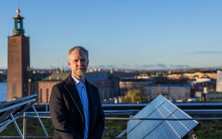 Person som står framför Stockholms Stadshus med solpaneler i fokus, en klar himmel i bakgrunden