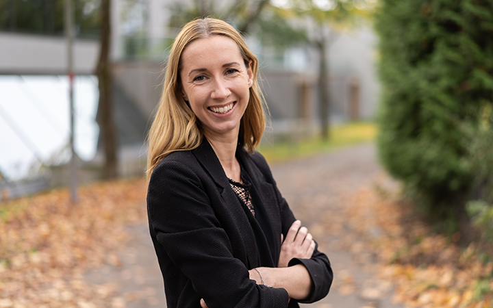 Leende Sara Thea Von Zernichow Sponheimsvart kavaj som står på en höstig stig med fallna löv