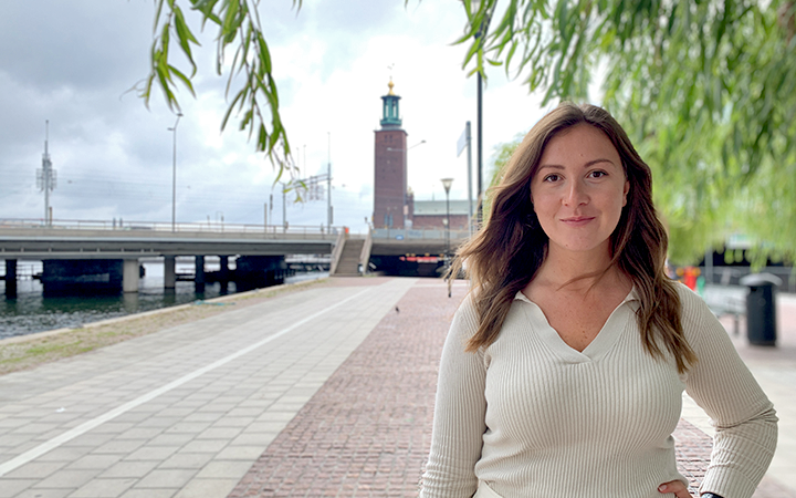 Kvinna framför Stockholms stadshus vid vattnet en molnig dag, Sverige