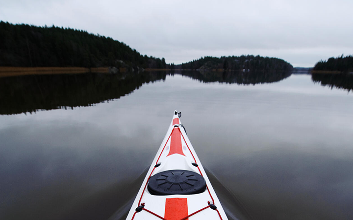 Kajakpaddling i en stilla sjö omgiven av skog under en molnig himmel i Sverige