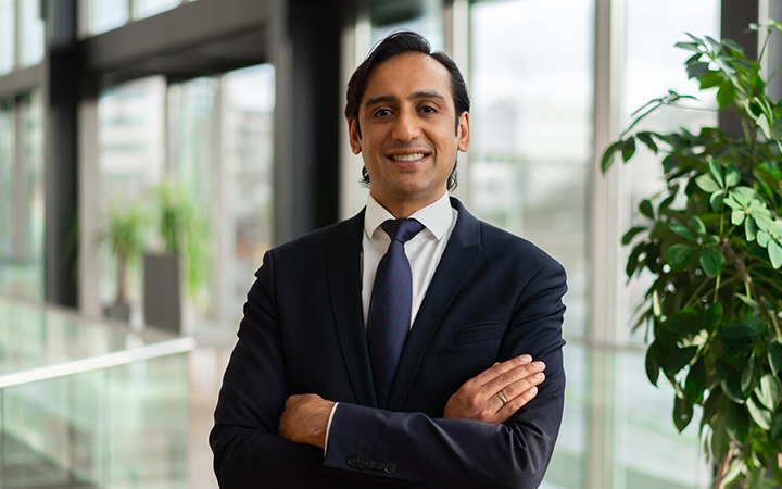 Affärsman i kostym står med armarna i kors i en modern kontorsmiljö