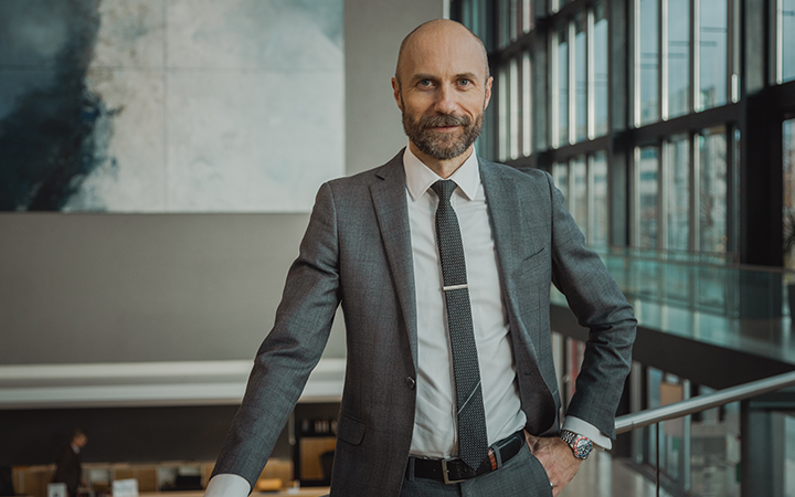 Affärsman i kostym står i ett modernt kontorsutrymme med stora fönster i bakgrunden