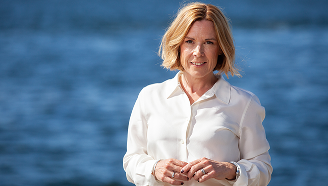 Kvinna i vit skjorta vid vattnet en solig dag