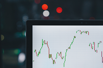 Diagram av aktiekurs med stigande och fallande trender på datorskärm, suddig bakgrund