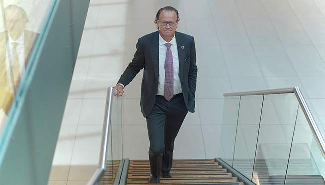 Man i kostym går uppför en trappa i en modern byggnad