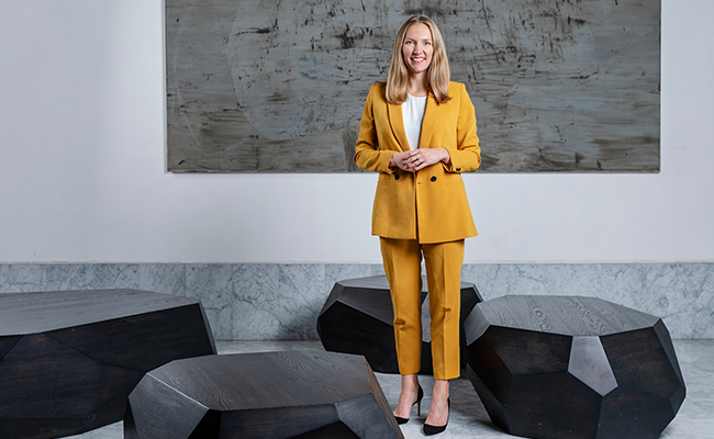 Johanna Lundgren senapsgul kostym står framför modern konst och geometriska bord
