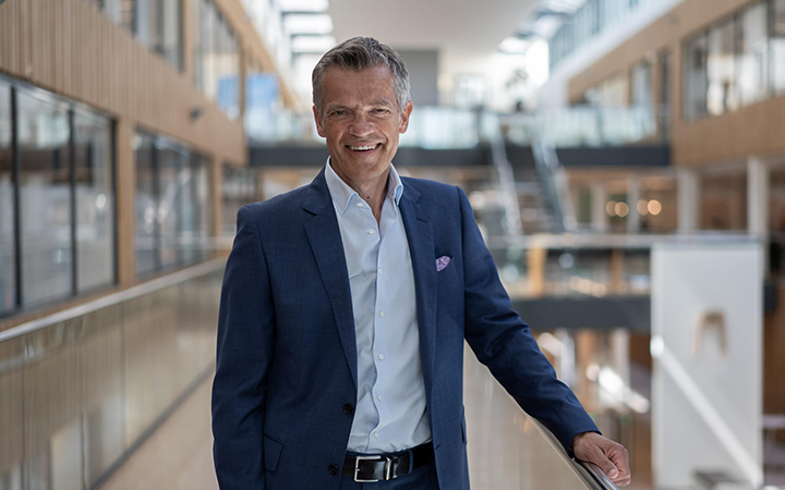 Jorgen Hjemdal i blå kostym som står i en modern kontorsmiljö med glasväggar och ljus interiör