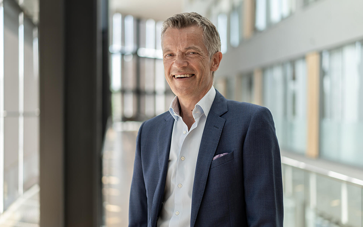 Man i kostym står i ljus kontorsmiljö och ler