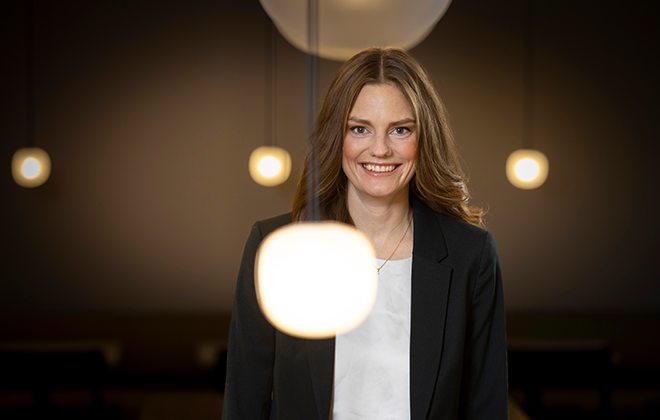 Leende kvinna i affärsdräkt med belysning i bakgrunden