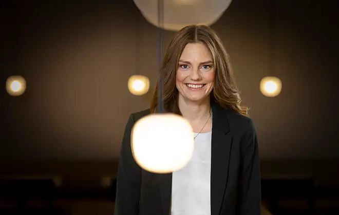 Leende kvinna i affärsdräkt med belysning i bakgrunden