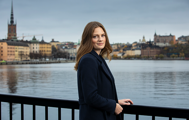 Kvinna vid vattnet med utsikt över Gamla stan i Stockholm, en molnig dag