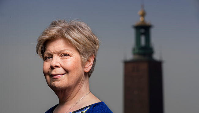 Kvinna framför Stockholms stadshus på en solig dag