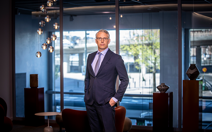 Man i kostym står i ett modernt kontor med stora fönster i bakgrunden