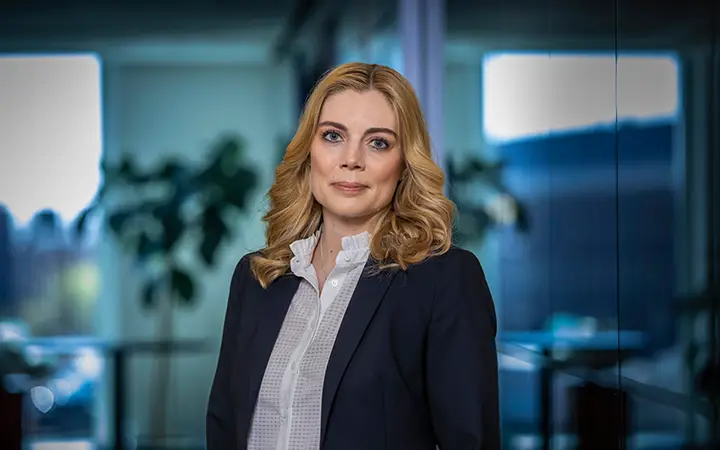 Therese Liden i affärskostym står i modernt kontorsmiljö med suddig bakgrund