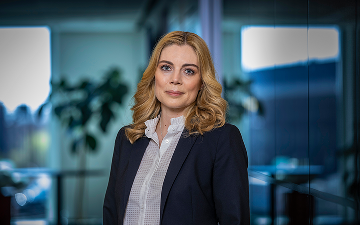 Therese Liden i affärskostym står i modernt kontorsmiljö med suddig bakgrund