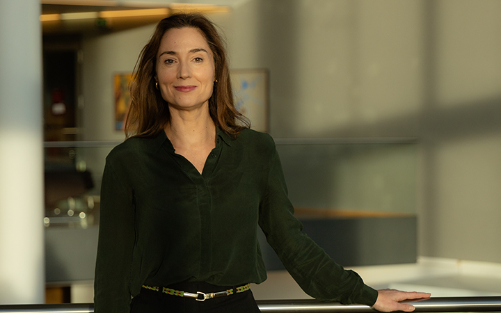 Kvinna i grön skjorta står i ett modernt kontorsutrymme