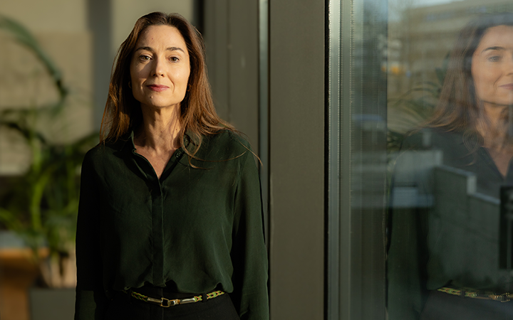 Tuliai grönt står vid ett fönster, reflekterad glasvägg, modernt inredningskontor i bakgrunden